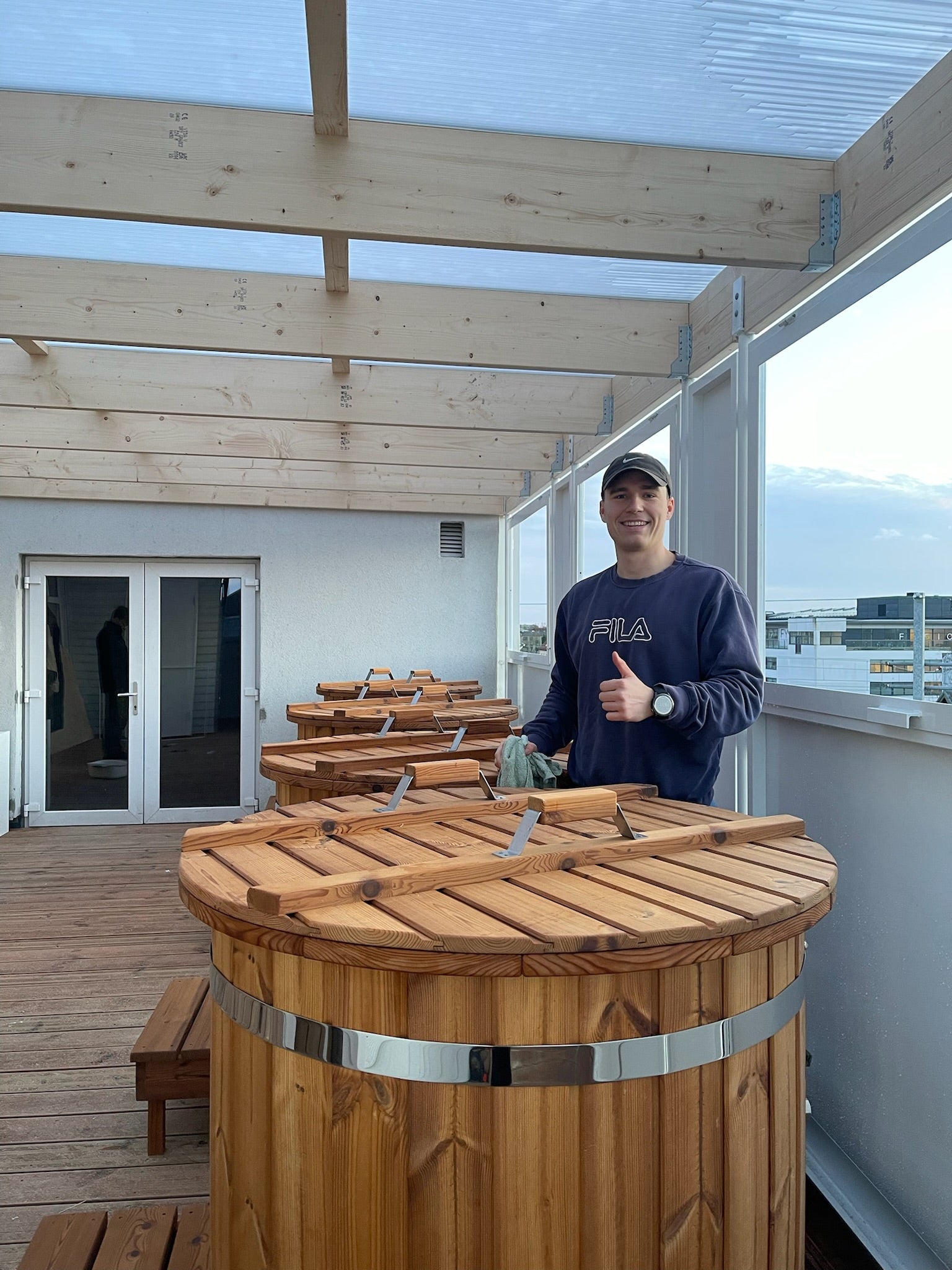 Mand ved træisbade med tommelfingeren opad på altan