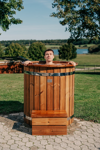 Mand i isbad udendørs med træisbad omgivet af grønt gras