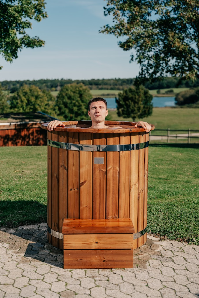 Mand i isbad udendørs med træisbad omgivet af grønt gras