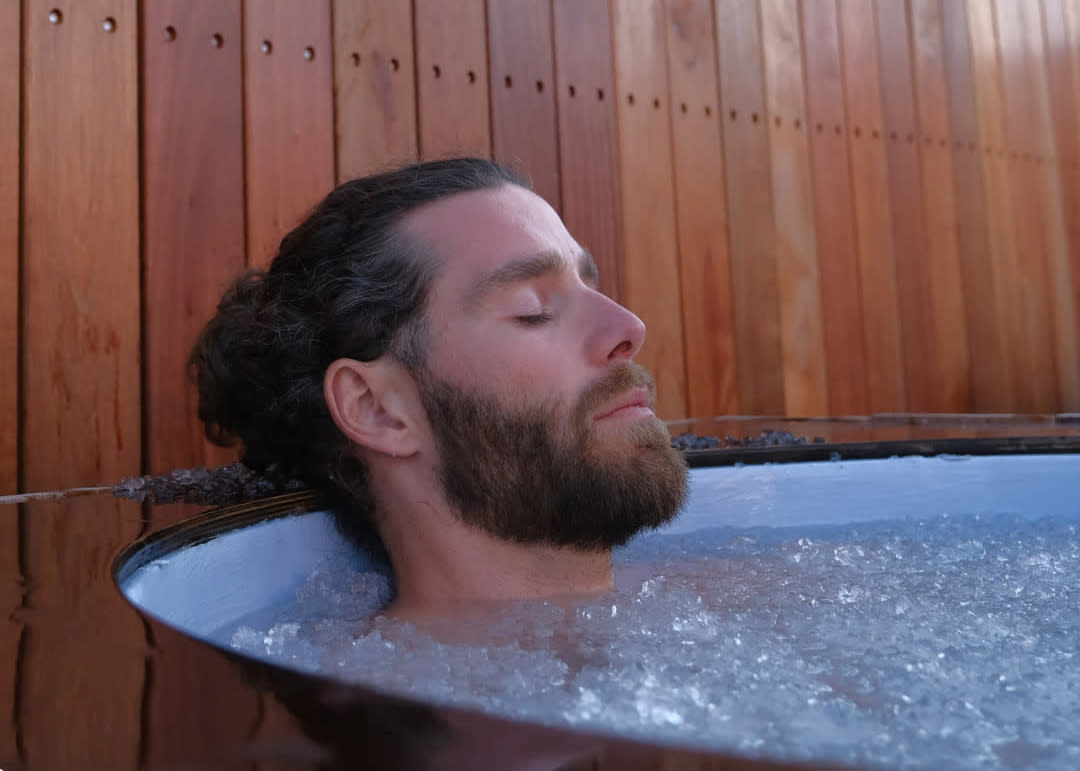 Mand i isbad med lukket øjne, ansigtet op ad vandet.